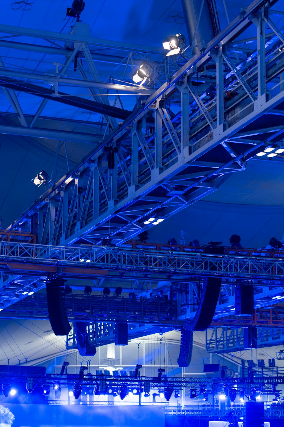 Overhead rigging with trusses, lights, and speakers in venue.