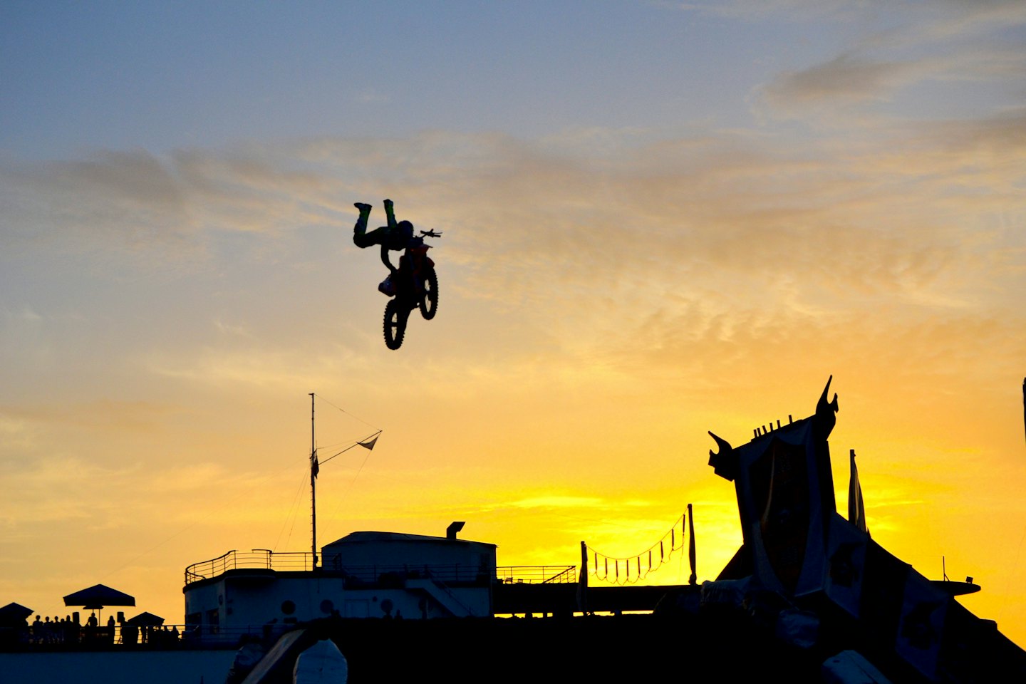 Motocross rider performs an inverted mid-air stunt at sunset.